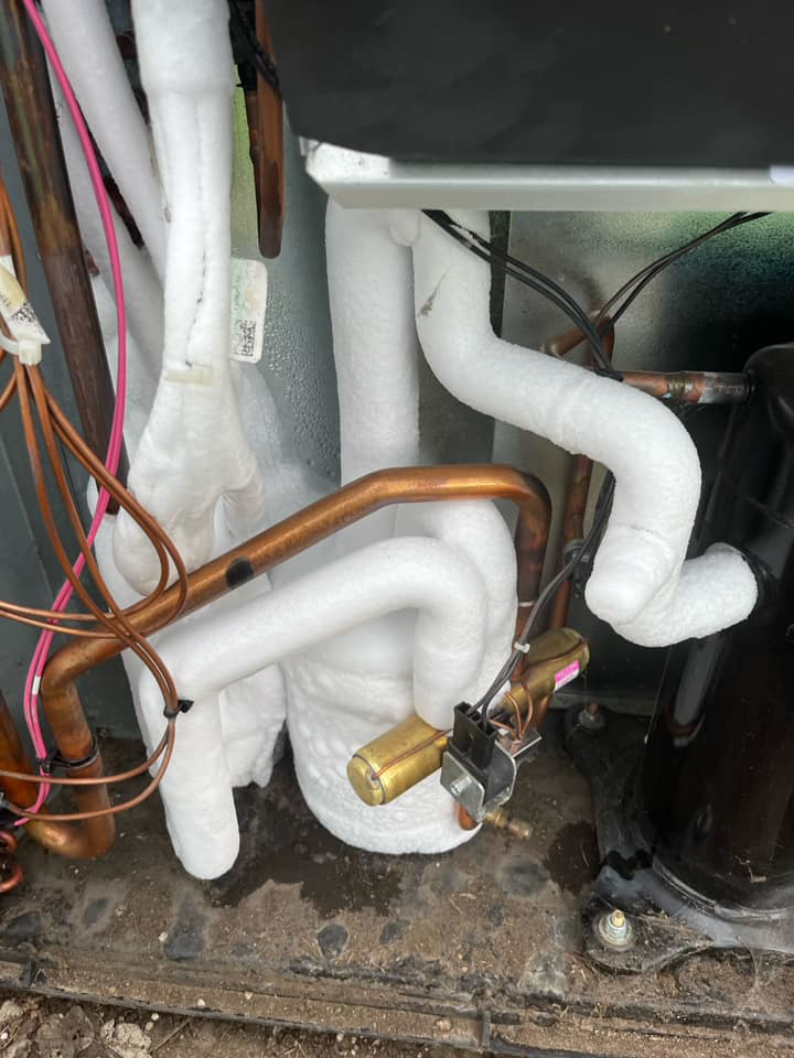 Close-up of frozen refrigerant lines and components on an outdoor HVAC unit, a common issue serviced by KATS Heating & Cooling in La Grange Park, IL.