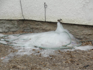 A frozen outdoor water spigot and hose, indicating a plumbing issue, serviced by EH Gochnauer & Sons, Inc. in Lancaster, PA.