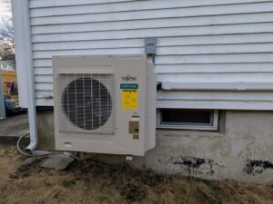A Fujitsu Airstage outdoor HVAC unit installed on the exterior of a home by WARM Global HVAC in East Providence, RI