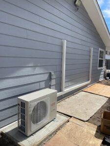 A Fujitsu mini-split outdoor condenser unit installed next to a residential building by National Heating & Cooling Company in Lakewood, CO.