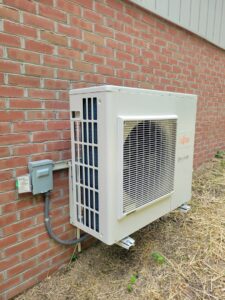 A Fujitsu mini-split heat pump outdoor unit installed on a brick wall by Complete Mechanical Solutions in Novi, MI