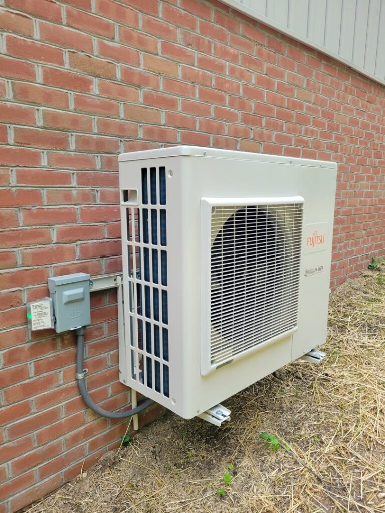 A Fujitsu mini-split heat pump outdoor unit installed on a brick wall by Complete Mechanical Solutions in Novi, MI