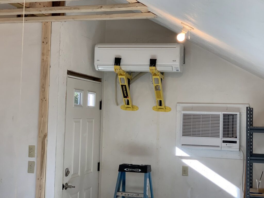 A Fujitsu mini-split indoor unit being installed with lifting straps by Elite Mechanical in Manchester, NH.