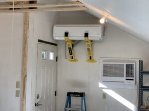 A Fujitsu mini-split indoor unit being installed with lifting straps by Elite Mechanical in Manchester, NH.