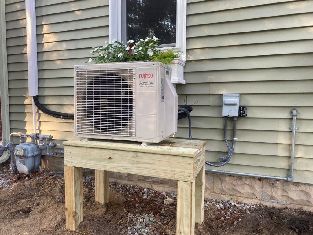A newly installed Fujitsu mini-split outdoor unit on a wooden stand by Tom's Heating & Air Conditioning LLC in Lacey Township, NJ.
