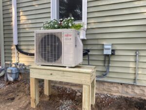 A newly installed Fujitsu mini-split outdoor unit on a wooden stand by Tom's Heating & Air Conditioning LLC in Lacey Township, NJ.