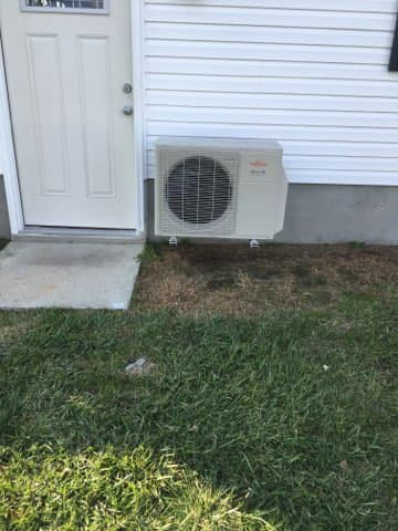 A Fujitsu mini-split outdoor HVAC unit installation next to a house door by James HVAC LLC in Georgetown, DE.