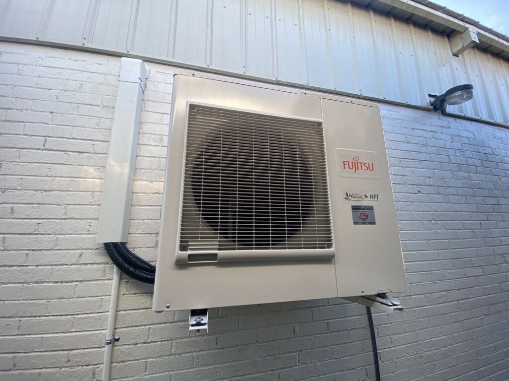 A Fujitsu outdoor mini-split HVAC unit installed on a brick wall by Eastergard HVAC in Greenville, SC.