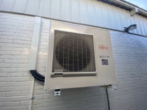 A Fujitsu outdoor mini-split HVAC unit installed on a brick wall by Eastergard HVAC in Greenville, SC.