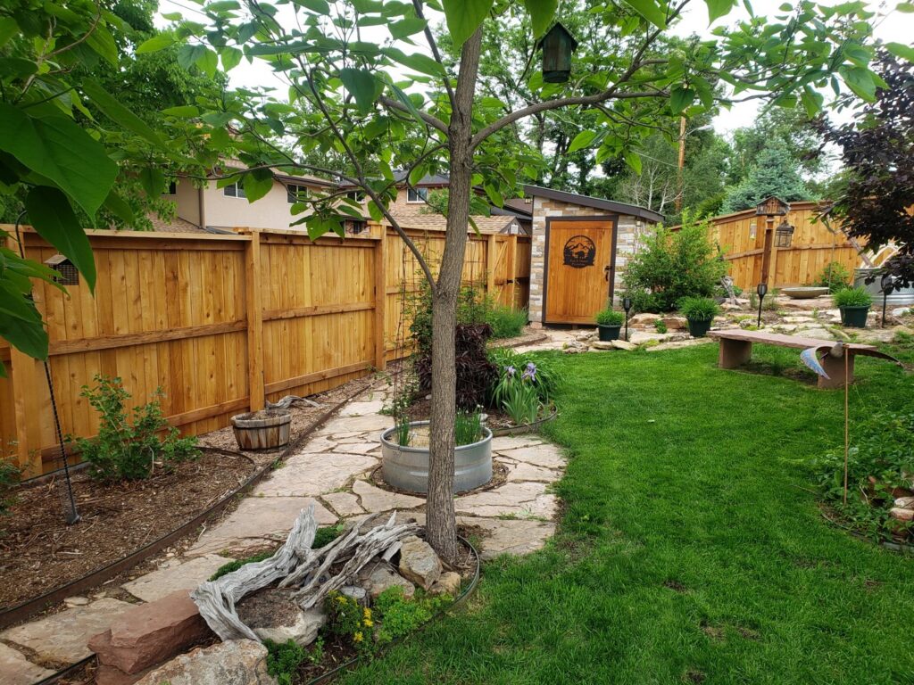 A beautiful full privacy wood fence installed in a landscaped backyard by Accent Fence & Design in Lakewood, CO.