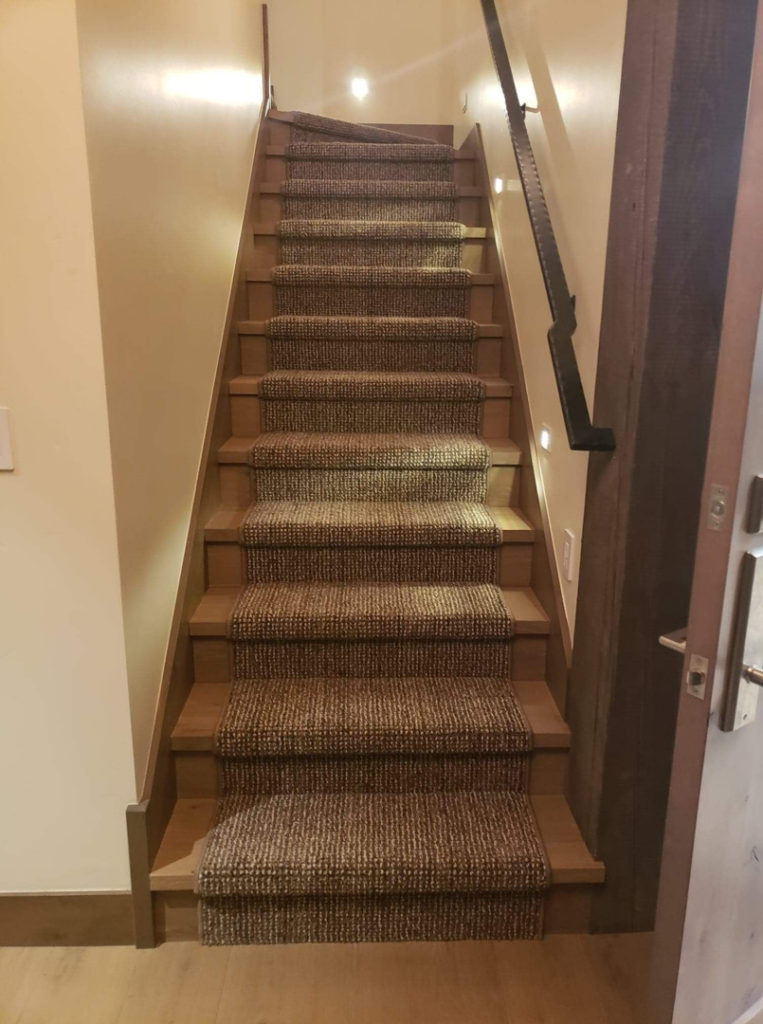 A full staircase featuring a brown textured carpet runner installed by Altered Edge in Kalispell, MT