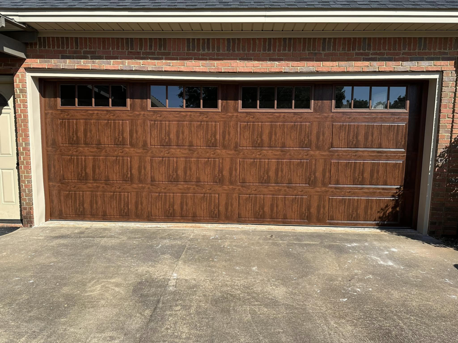 A full view of a newly installed brown garage door with windows on a brick house by Mike's Garage Door Repair in Wetumpka, AL.