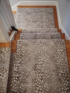 Full view of a custom patterned carpet runner expertly installed on a wooden staircase by Persian Rug Gallery in Nashua, NH.