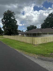 A wide view of a newly installed wooden picket fence enclosing the front and side yard by J&L Fence in Zolfo Springs, FL.