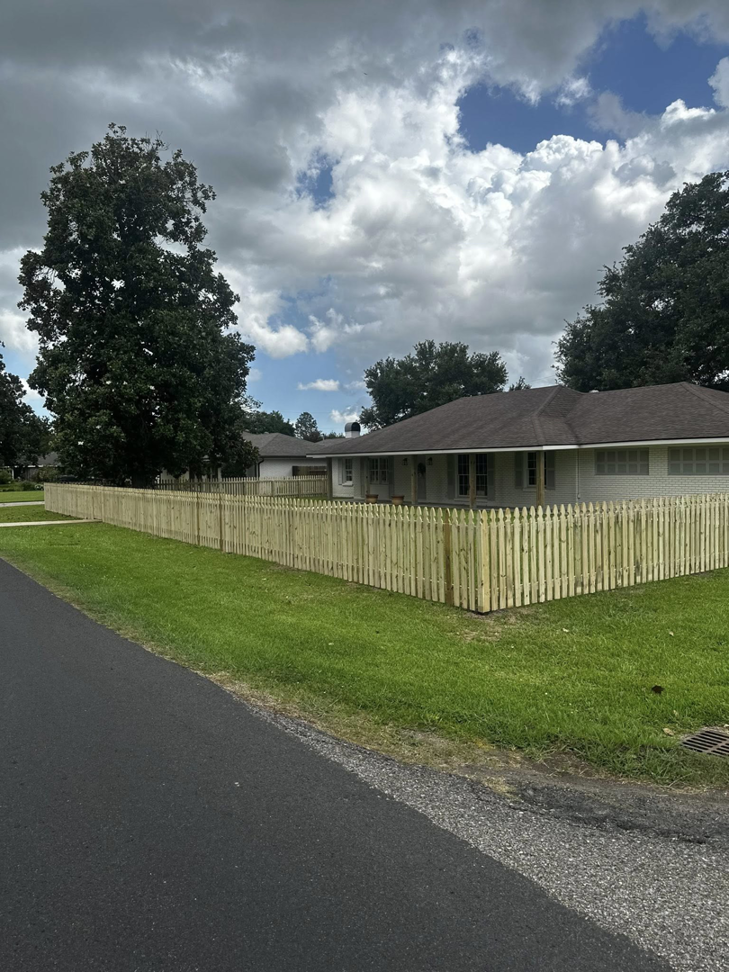 A wide view of a newly installed wooden picket fence enclosing the front and side yard by J&L Fence in Zolfo Springs, FL.