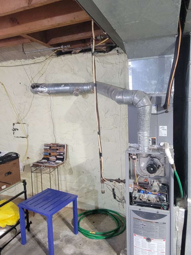 An indoor furnace or air handler unit with connected ductwork in a basement by Friess Heating & Air Conditioning in Topeka, KS