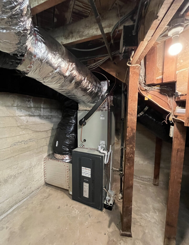 A furnace and air handler unit with ductwork in a crawl space by 20th Century Heating and Air in Anaheim, CA.