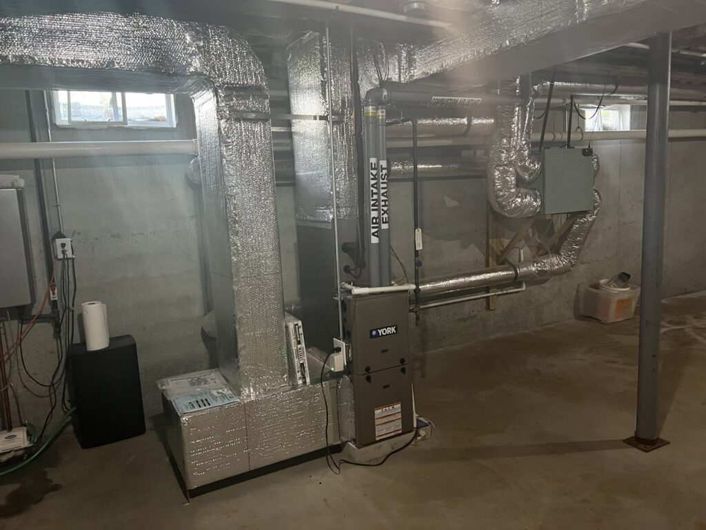 A new furnace and air handler unit with extensive ductwork installed in a basement by All Points HVAC in Worcester, MA.