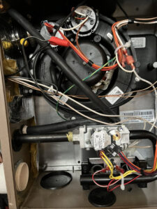 The complex interior components of a furnace or air handler, showing wiring and pipes during an HVAC service by Greenley Heating & Cooling in Waterloo, IA