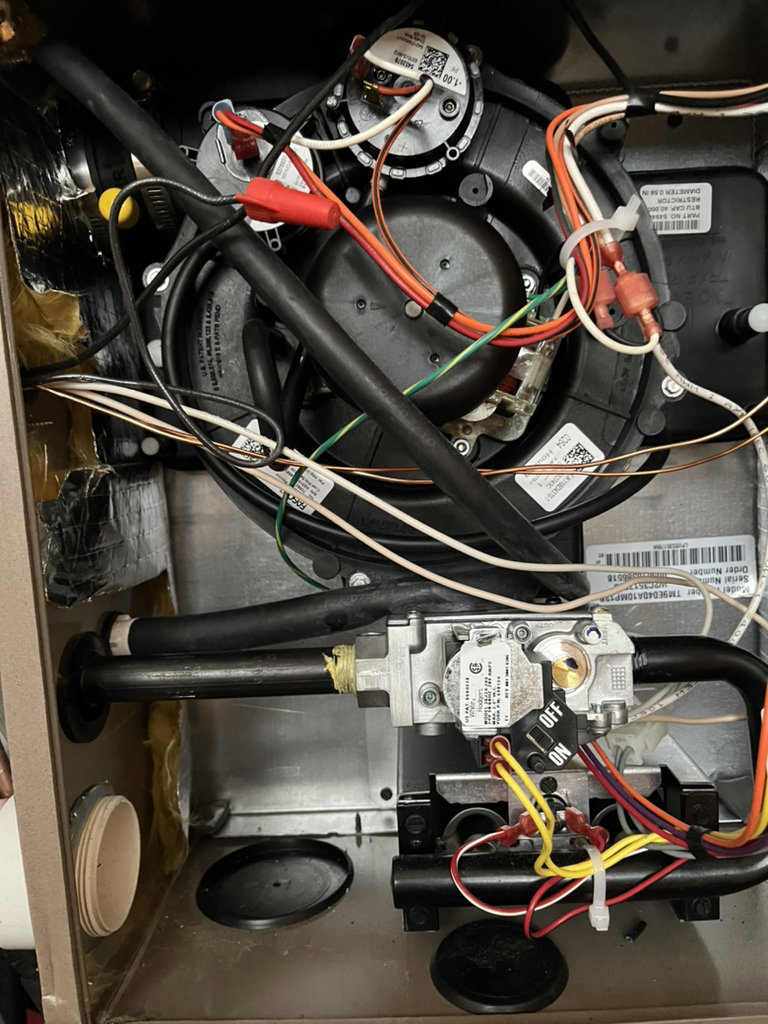 The complex interior components of a furnace or air handler, showing wiring and pipes during an HVAC service by Greenley Heating & Cooling in Waterloo, IA