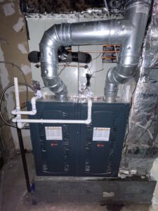A furnace or air handler unit with metal ductwork and PVC piping installed by Elite Home Comfort in Clarksville, TN