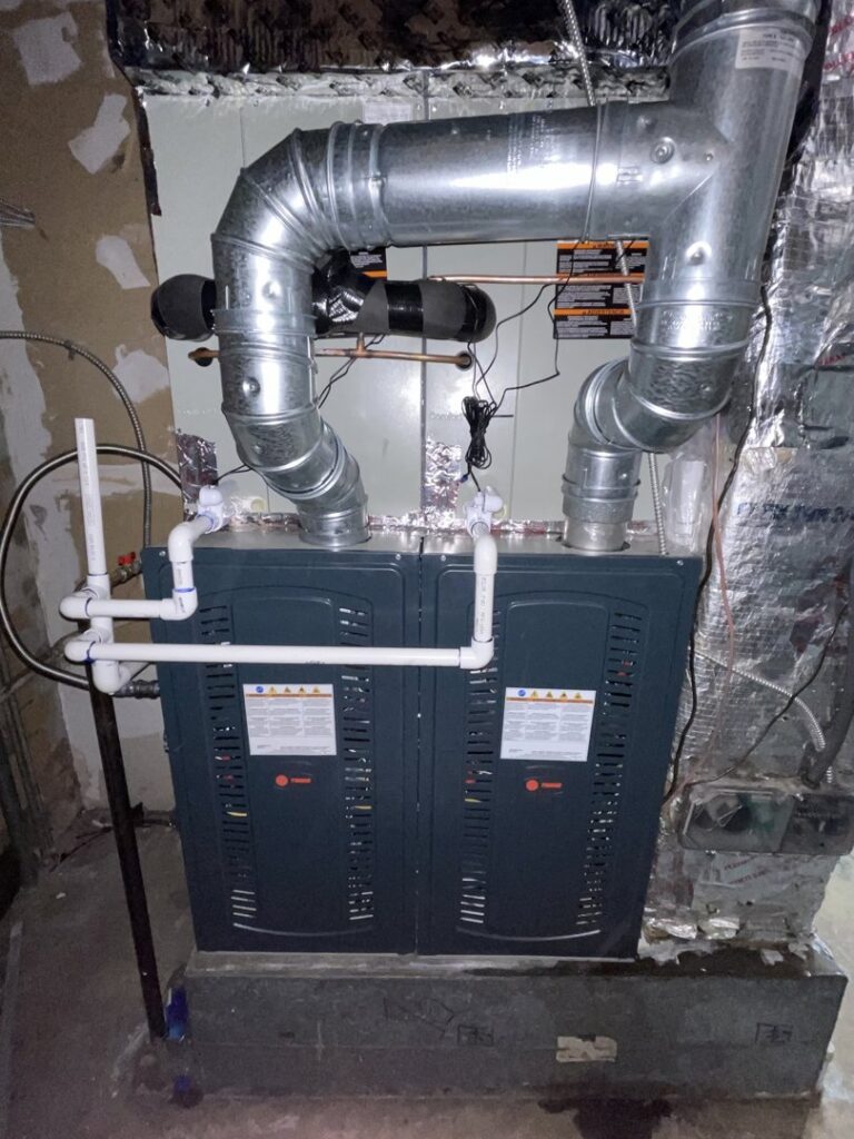 A furnace or air handler unit with metal ductwork and PVC piping installed by Elite Home Comfort in Clarksville, TN