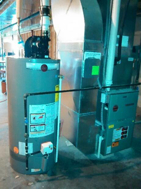 A furnace and water heater installed together in a utility area by Cheaper Plumbing & Heating in Lansing, MI