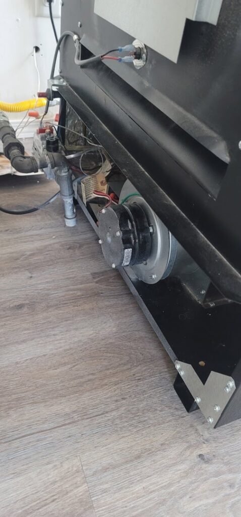 Close-up view of a furnace's internal blower motor and gas lines, indicating HVAC service by Northern Peak Heating & Cooling in Bozeman, MT.