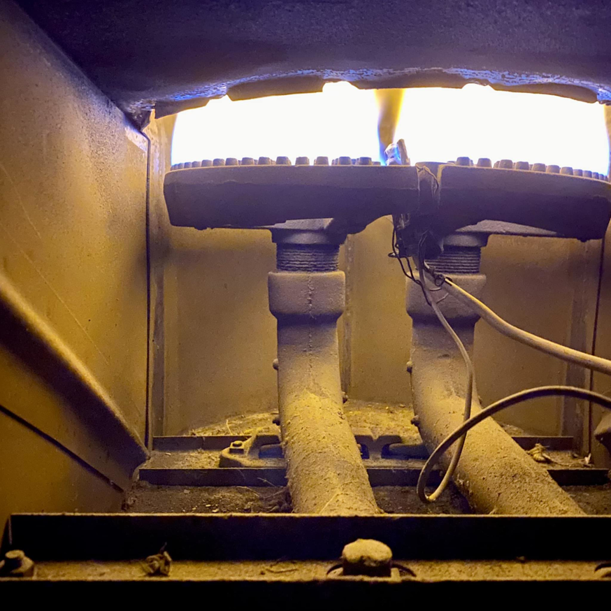 Close-up of a furnace burner with visible flames, indicating heating system operation by Northside Mechanical in Des Plaines, IL.