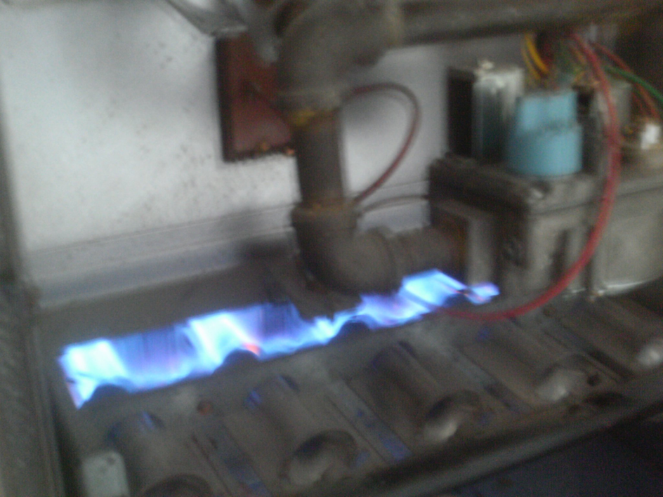 A close-up view of a furnace burner with blue flames, indicating proper operation, by Geddes Heating and Cooling in Aurora, CO.