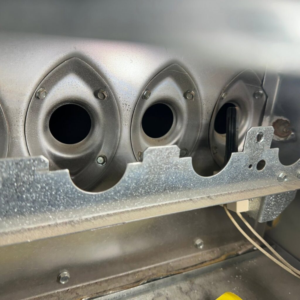 Close-up view of furnace burners and igniter during an inspection or service by Jump HVAC in Lakewood, CO.