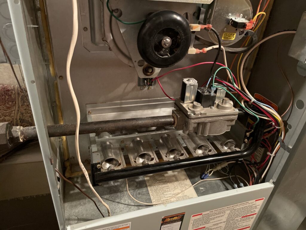 Close-up view of furnace burners and gas lines during an inspection or repair by Your HVAC Guy in Aurora, IL.