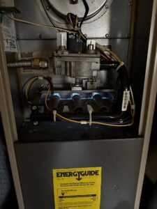 An interior view of a furnace with its burners lit, demonstrating a functional heating system by Elite Heat & Air in Monroe, LA.