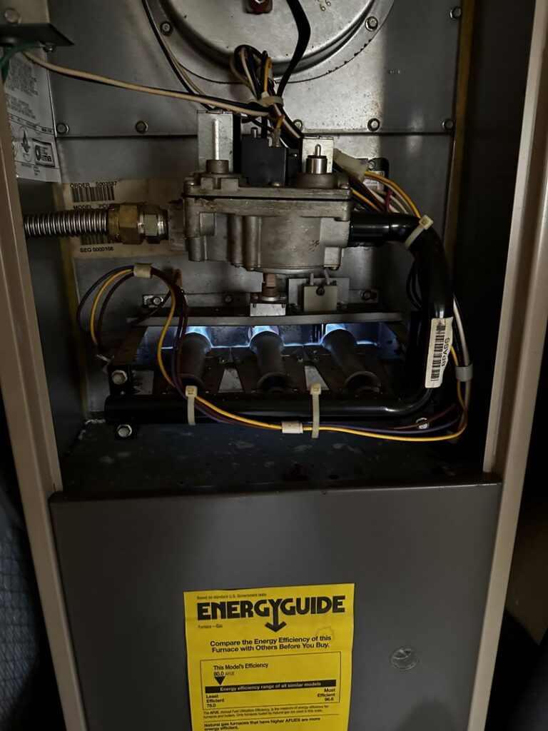 An interior view of a furnace with its burners lit, demonstrating a functional heating system by Elite Heat & Air in Monroe, LA.