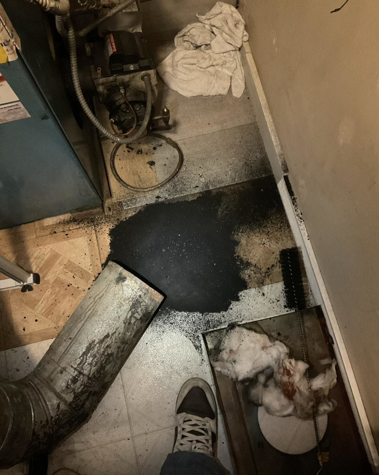 Soot and debris on the floor during a furnace cleaning or repair job by Black Oak HVAC in Derry, NH