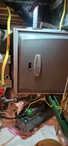 Close-up of an Armstrong Air furnace with a condensate pump and piping, indicating HVAC service by Northern Peak Heating & Cooling in Bozeman, MT.