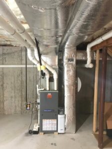 A residential furnace and insulated ductwork in a basement, part of an HVAC system by Aspen Air Duct Cleaning in Methuen, MA.