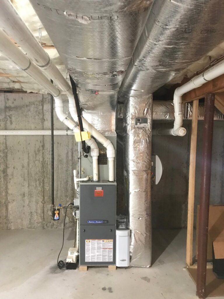 A residential furnace and insulated ductwork in a basement, part of an HVAC system by Aspen Air Duct Cleaning in Methuen, MA.