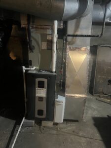 A furnace and air handler unit with an attached humidifier in a basement by Breezy Brothers Heating and Cooling in Lafayette, IN.