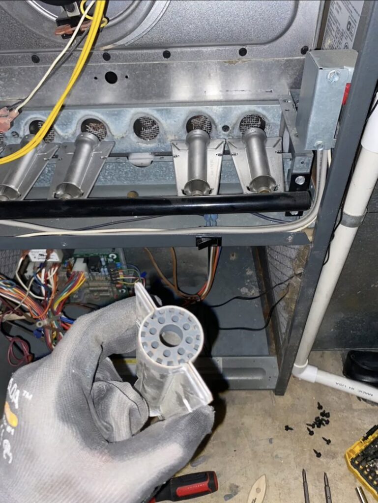 A technician holding a furnace igniter during a repair or replacement by Infinite Heating & Air in Newnan, GA.