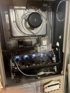 The interior of a residential furnace with burners actively lit, demonstrating heating system operation by Greenley Heating & Cooling in Waterloo, IA