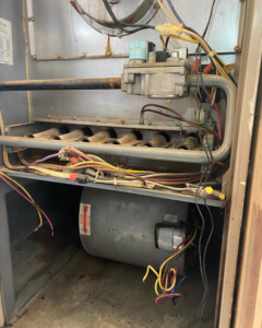 An HVAC technician inspecting the interior of a furnace at B & H Heating and Air Services LLC in Local City, ST.