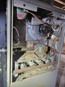 The interior of a furnace showing burners and blower motor during maintenance by Bakes Heating and Cooling in Chatham, IL.