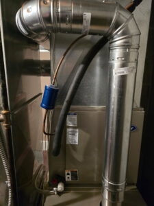 A furnace unit with refrigerant lines and ductwork installed by Jackson Home Appliance Heating & Cooling in Omaha, NE