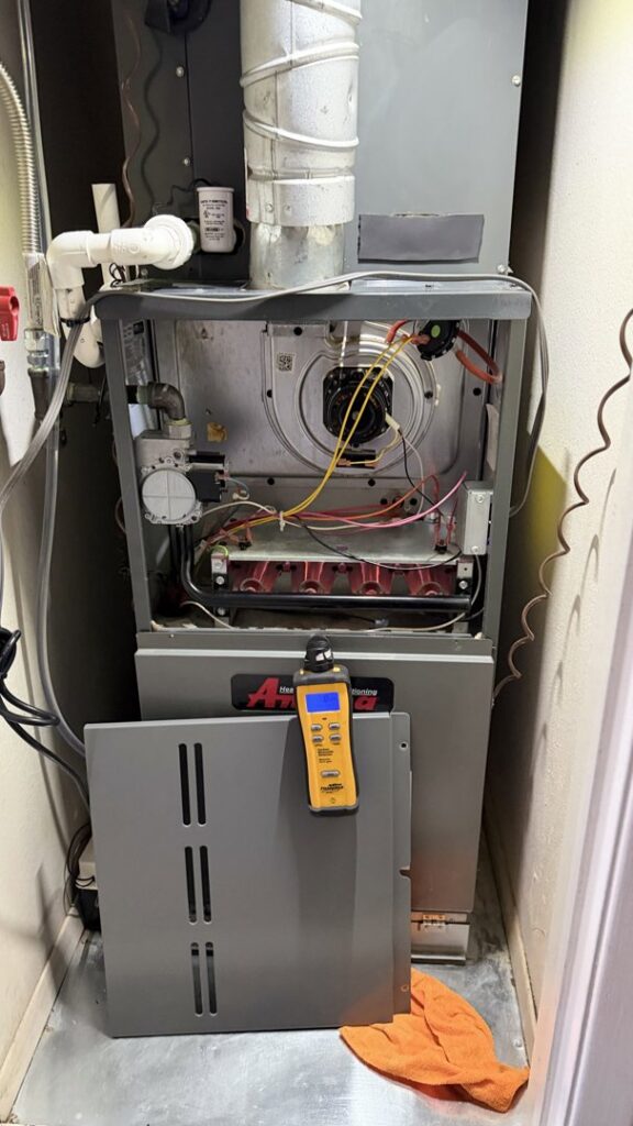 An HVAC technician performing a furnace repair with a diagnostic tool on an open unit by EA Heating & Cooling in El Paso, TX.