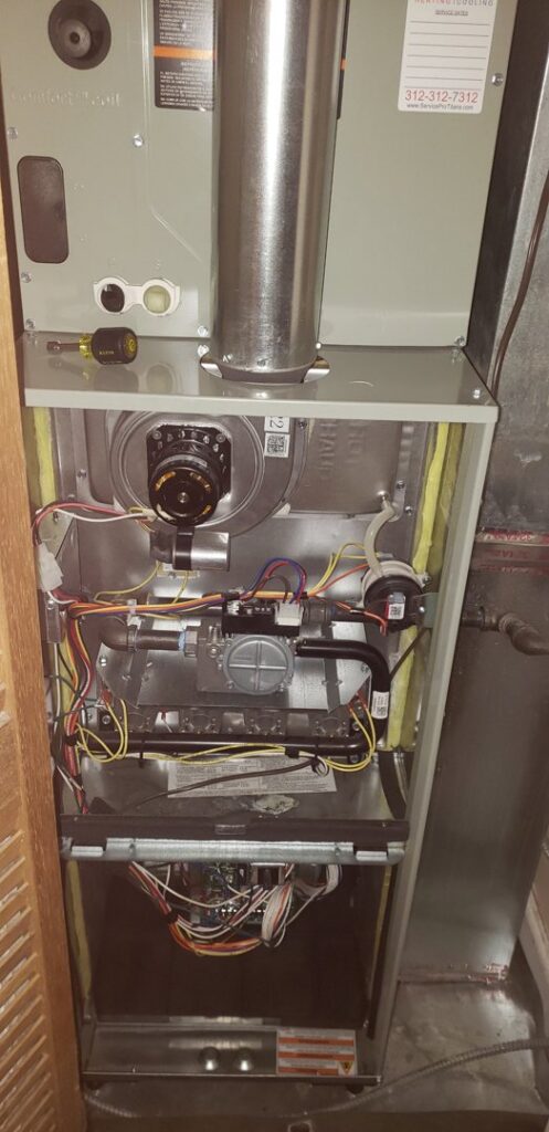An open furnace unit revealing internal components and wiring during repair or maintenance by Service Pro Titans, Chicago, IL.