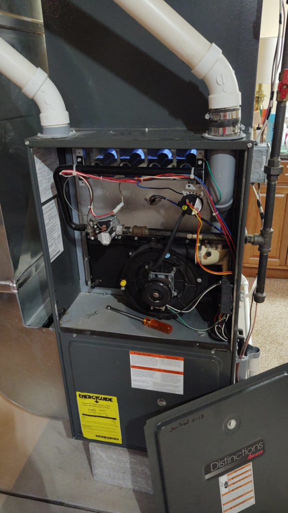 An open furnace panel showing internal components during a repair or maintenance service by SM Heating and Cooling in Rochester, NY