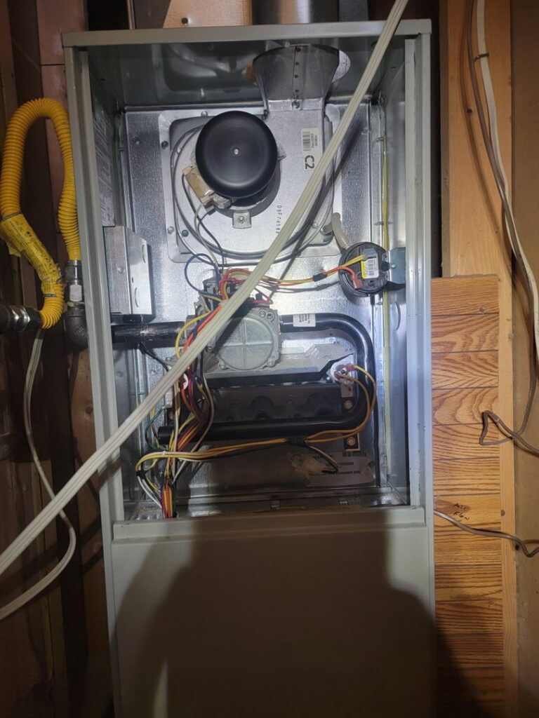 An open furnace showing internal components during repair or maintenance by Working Wolves Heating & Cooling LLC in Lawrence, KS.