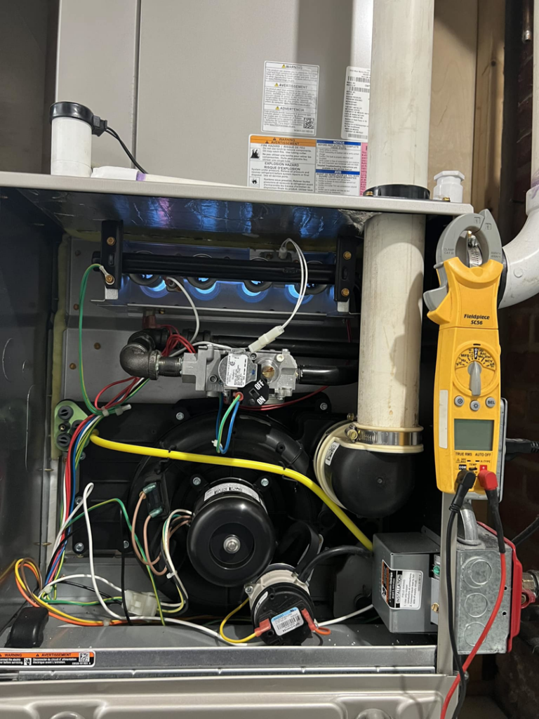 An open furnace unit showing internal components and a clamp meter during a service call by aghapy 1 in Jersey City, NJ