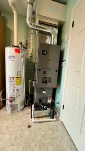A furnace and water heater installed in a utility room, showcasing services by Adam's HVAC in Naperville, IL.